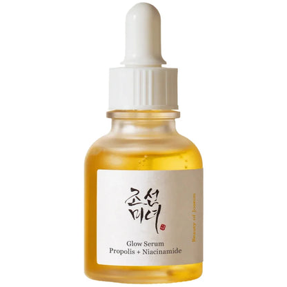 A clear glass dropper bottle filled with golden-yellow serum, featuring a white label with Korean text and 'Glow Serum Propolis + Niacinamide' printed below, set against a plain white background.