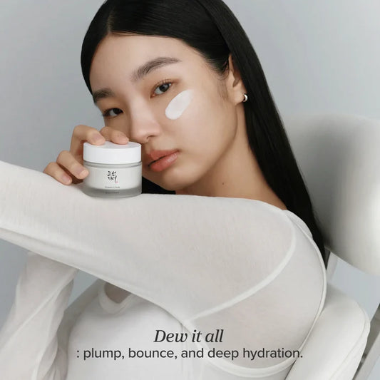 Woman holding a skincare product with text 'Dew it all' on a neutral background