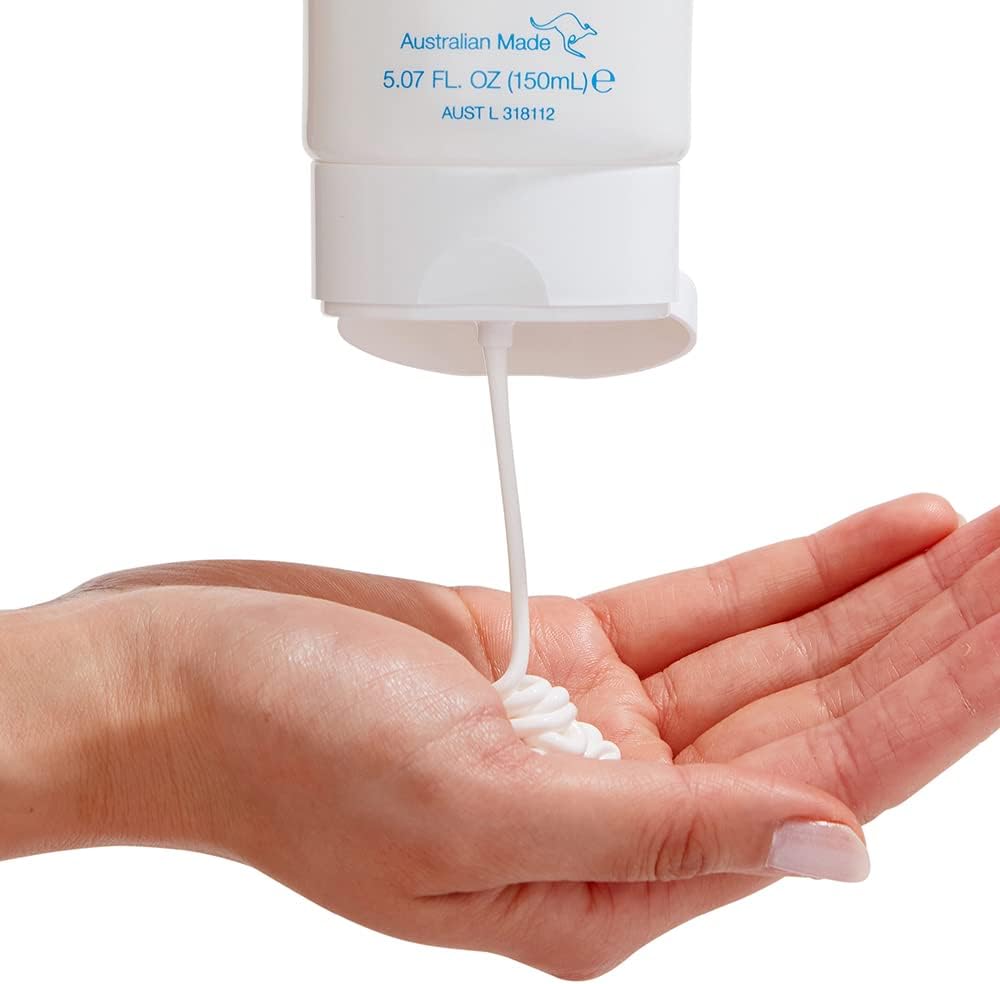 Hand holding a Bondi Sands Sunscreen Lotion SPF50+ Fragrance Free 150ml white bottle with cream being dispensed onto the palm against a white background