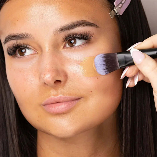 Model applying foundation with Brushworks Foundation Brush for smooth, even coverage and professional results.