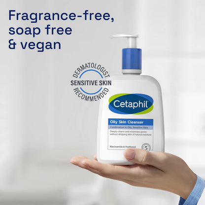 Cetaphil oily skin cleanser bottle held in a hand with 'Fragrance-free, soap free & vegan' text on a light gray background.