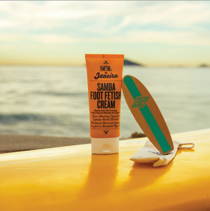Sol de Janeiro Samba 2-Step Foot Fetish Care 90ml and foot smoothing board on a surfboard near the shore.