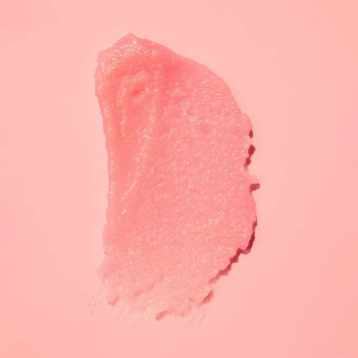A textured smear of sparkling pink cosmetic cream or gel on a solid pink background.