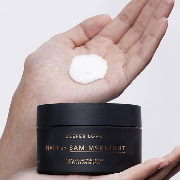 Black jar of 'Deeper Love Hair by Sam McKnight' treatment mask with a dollop on a hand against a white background