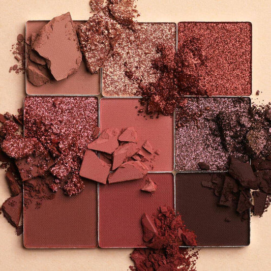 Huda Beauty Makeup palette with crushed eyeshadow shades on a beige background