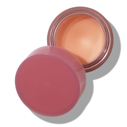 Cosmetic cream in a round container with a pink lid on a white background
