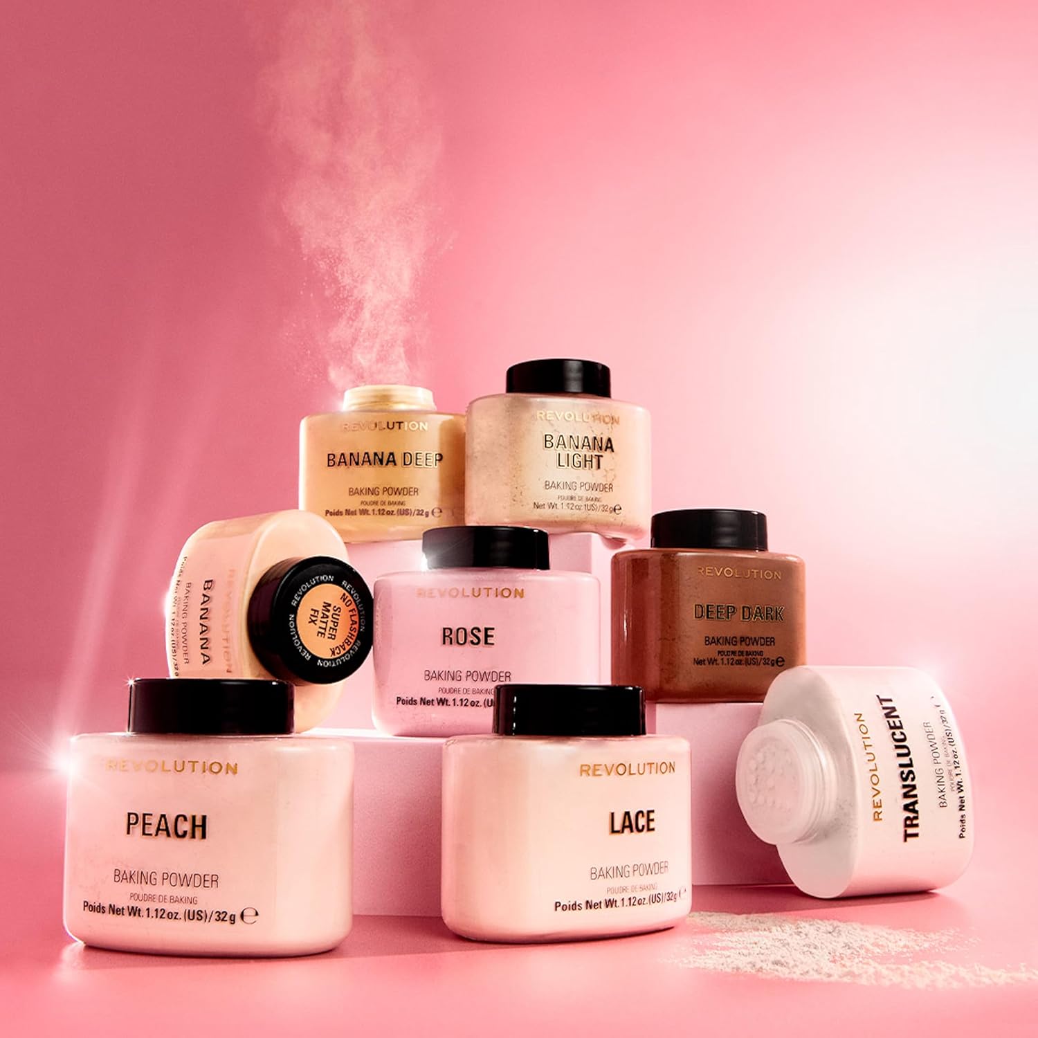 Collection of Makeup Revolution baking powder jars on a pink background