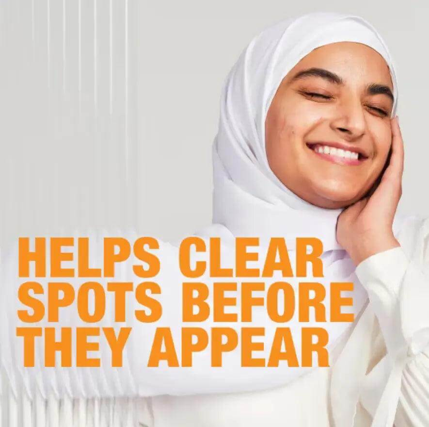 Smiling young woman in a hijab promoting Neutrogena Spot Stress Control Scrub for clear skin.