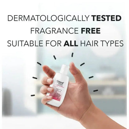 Hand holding a bottle of Nizoral shampoo with text about dermatological testing and suitability for all hair types.