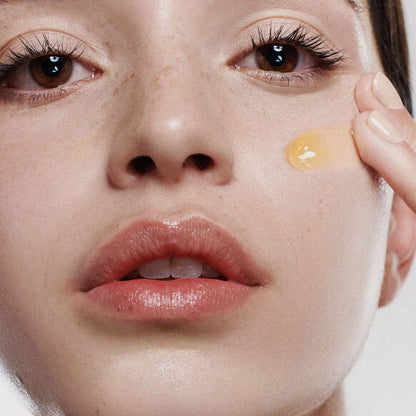 Close-up of a person applying a skincare product to their face.