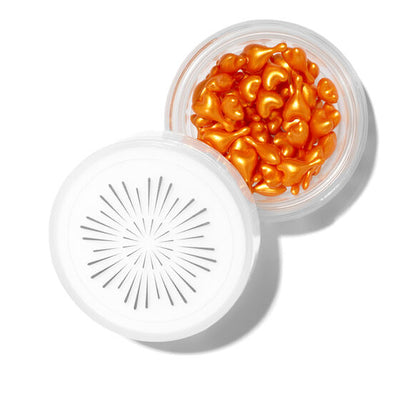 Jar of orange Oskia London Vitamin C capsules with a white lid on a white background