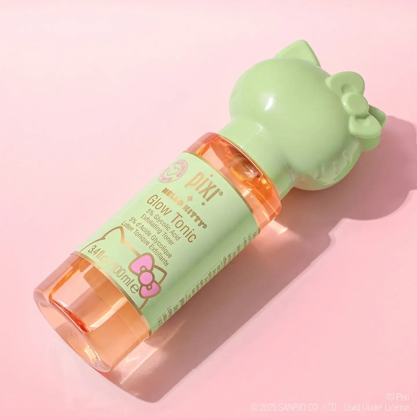Pixi + Hello Kitty Glow Tonic 100ml bottle on a pink background, perfect for radiant skincare on the go.