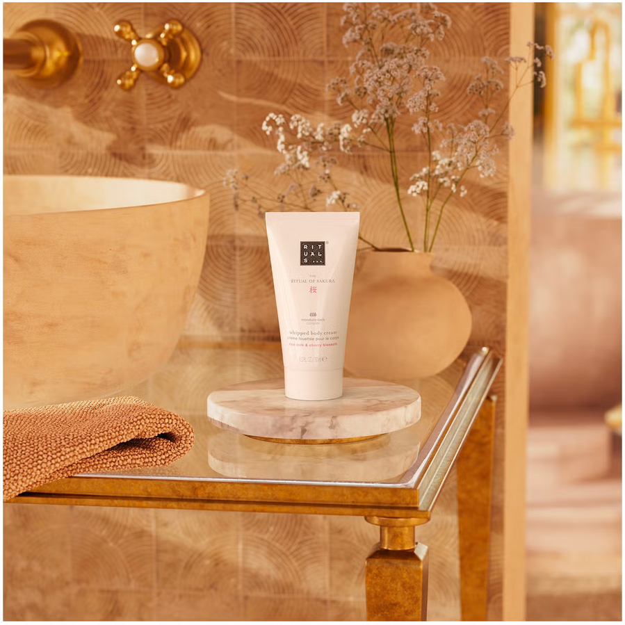 Rituals: Tube of cream on a marble slab with a decorative vase and flowers in the background