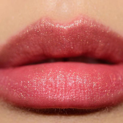 Close-up of satin lips wearing NARS Lipstick - Orgasm, showcasing its radiant pink hue and luxurious finish.