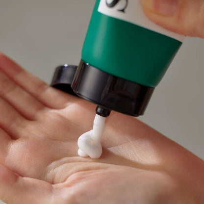 Green and black pump applying white cream to a hand