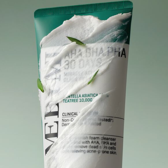 Tube of facial cleanser with green and white design on a light gray background