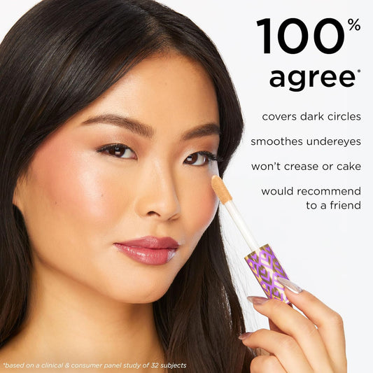 Woman applying TARTE Shape Tape Concealer concealer with a makeup stick on a white background, featuring product text.