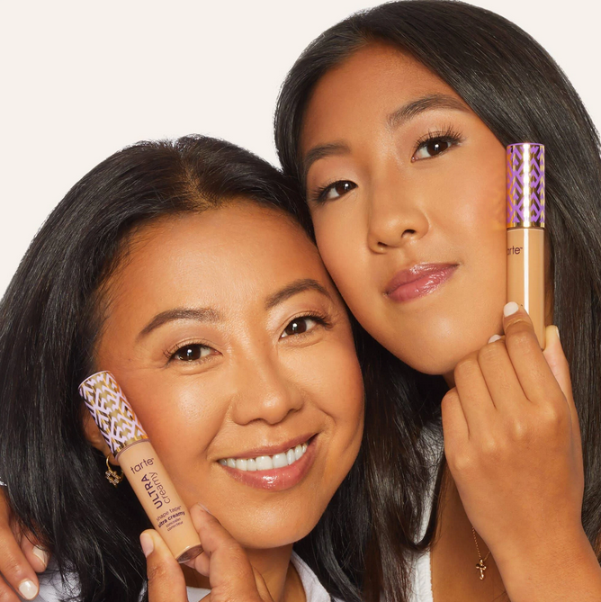 Two women holding makeup products against a white background TARTE Shape Tape Concealer