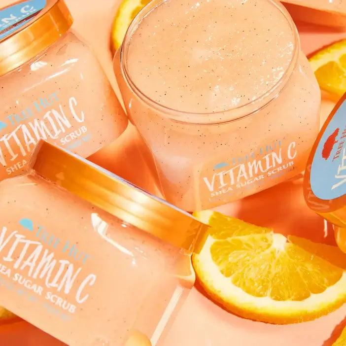 Jars of TREE HUT Vitamin C scrub with orange slices on a pink background