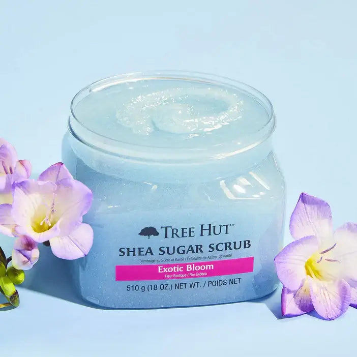 Jar of Tree Hut Shea Sugar Scrub with flowers on a light blue background