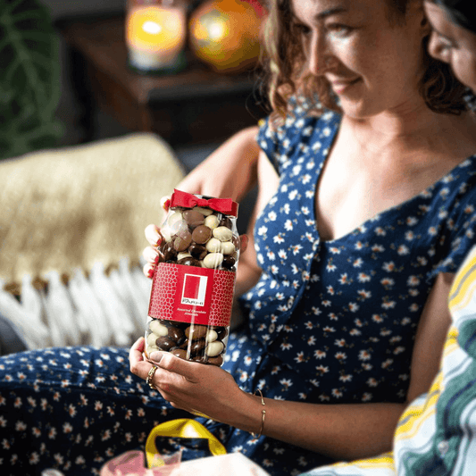 Two people enjoying luxury chocolate covered almonds in elegant jar, perfect for gifting and special occasions.