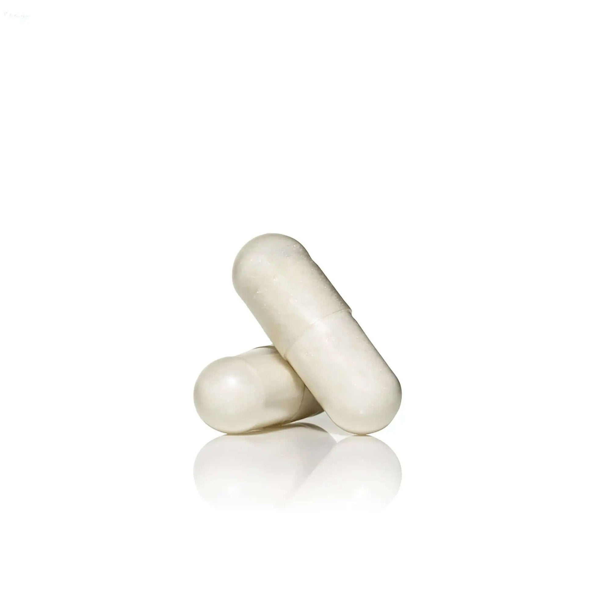 Two white capsules of Advanced Nutrition Programme™ Skin Youth Biome on a reflective surface.