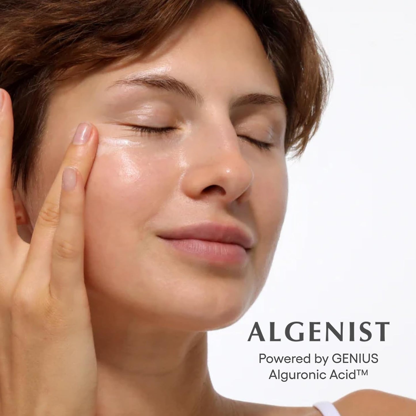 Woman applying cream to her face with 'Algenist' branding in the background