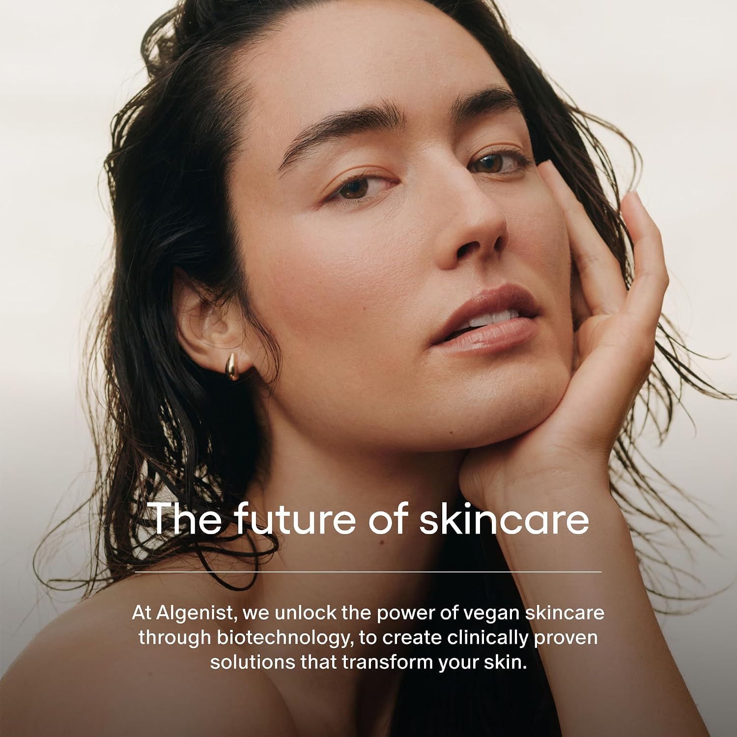 Woman with hand on face against a neutral background with Algenist skincare brand text.