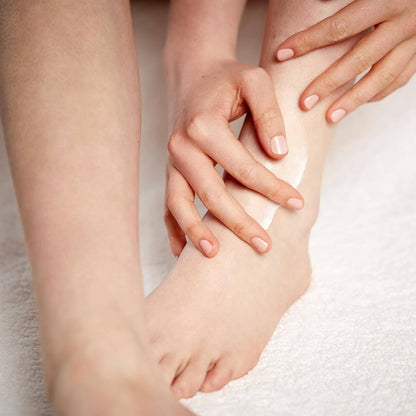 Applying AMELIORATE® Intensive Foot Treatment to smooth, hydrate dry feet on a soft towel.
