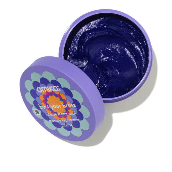 Amika Bust Your Brass Cool Blonde Intense Repair Hair Mask in a purple jar, designed to eliminate brassy tones in blonde hair.