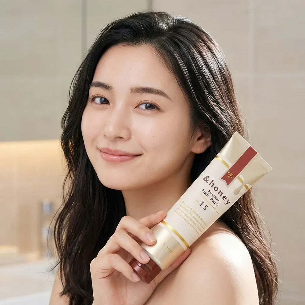 Woman holding a &honey hair care product with a neutral background