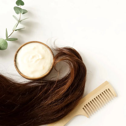 Hair care product with a wooden bowl, comb, and eucalyptus leaves on a white background