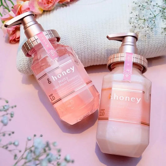 Two bottles of 'honey' skincare products on a pink background with flowers.