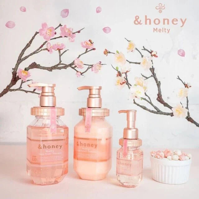 Three skincare bottles with 'honey' branding in front of cherry blossom branches.