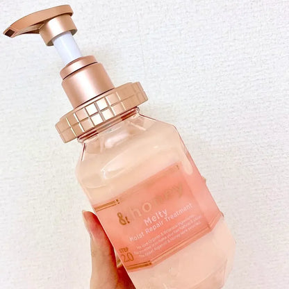 Bottle of '& ho Melty Multi Repair Treatment' with a rose gold pump on a white background