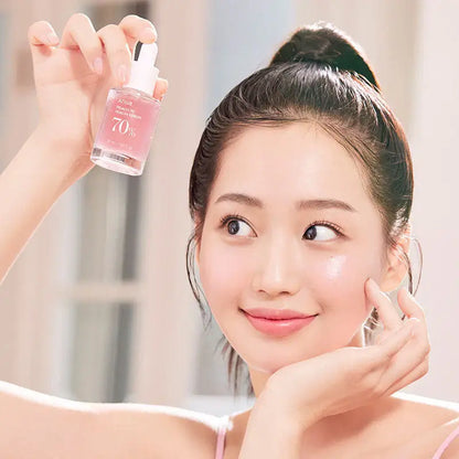 Model promoting Anua Peach 70% Niacinamide Serum, showcasing radiant skin and a fresh skincare routine.
