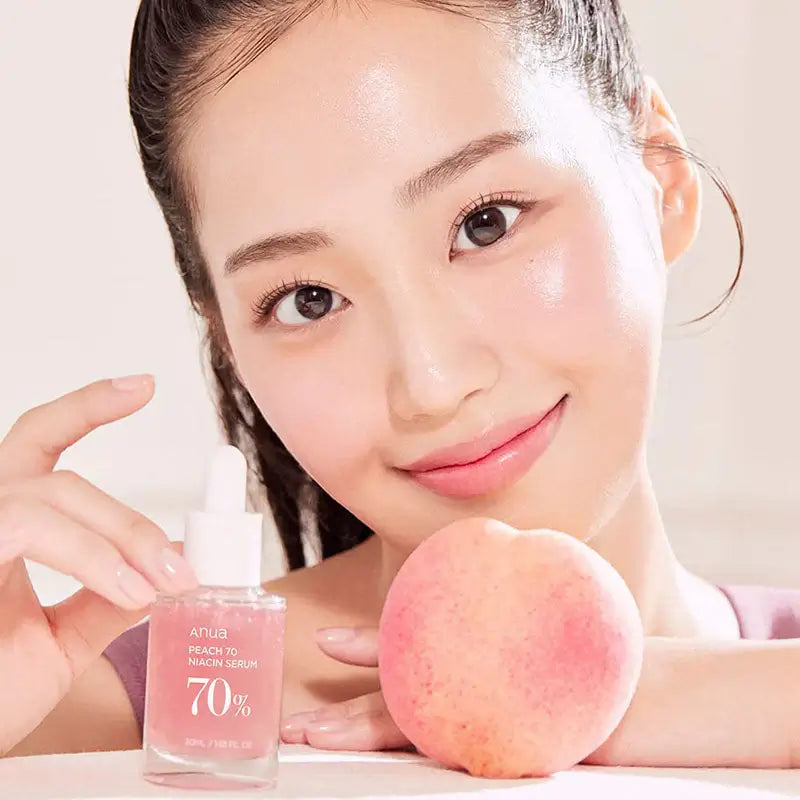 Anua Peach 70% Niacinamide Serum shown with a fresh peach and a smiling model, highlighting radiant skin benefits.