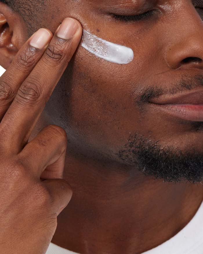 Man applying cream to his face with a close-up focus on the action.