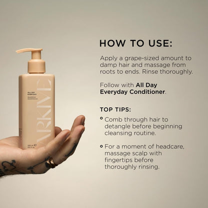 Hand holding an ARKIVE bottle of shampoo with usage instructions on a neutral background