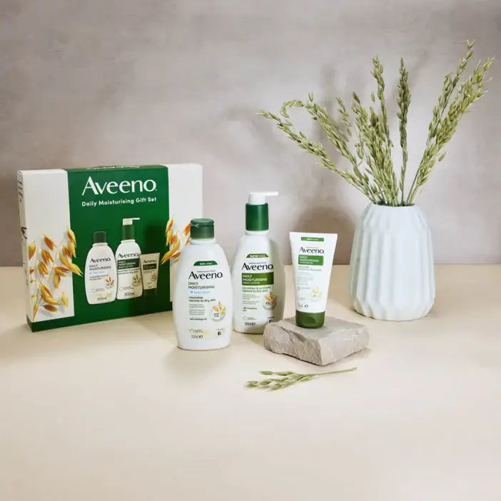 Aveeno Daily Moisture Range 3 Piece Gift Set displayed with packaging and flowers for hydrated skin.