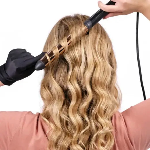 Person using BaByliss Titanium Brilliance Waves Wand to create soft waves with long, wavy blonde hair.