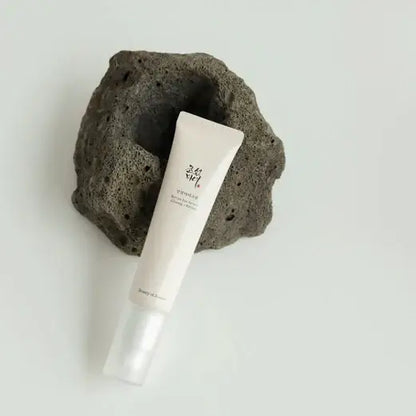 Beauty Of Joseon Revive Eye Serum 30ml tube on a textured stone surface, showcasing anti-aging skincare benefits.