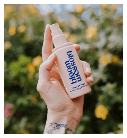 Bloom and Blossom Spritzy Toes Revitalising Leg and Foot Spray in hand, ideal for soothing tired legs and feet.