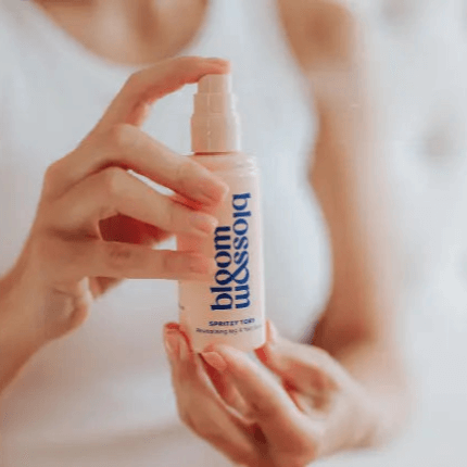 Bloom and Blossom Spritzy Toes Revitalising Leg and Foot Spray in a hand, showcasing its easy application.