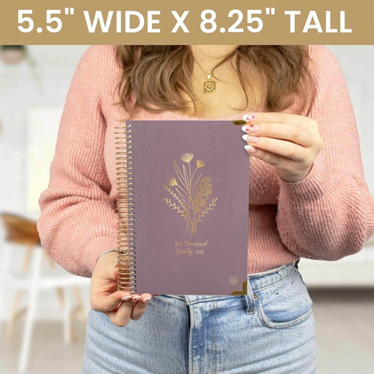 Bloom Daily Planners HARDCOVER 2026 held by a woman, showcasing floral design, 5.5" wide x 8.25" tall.