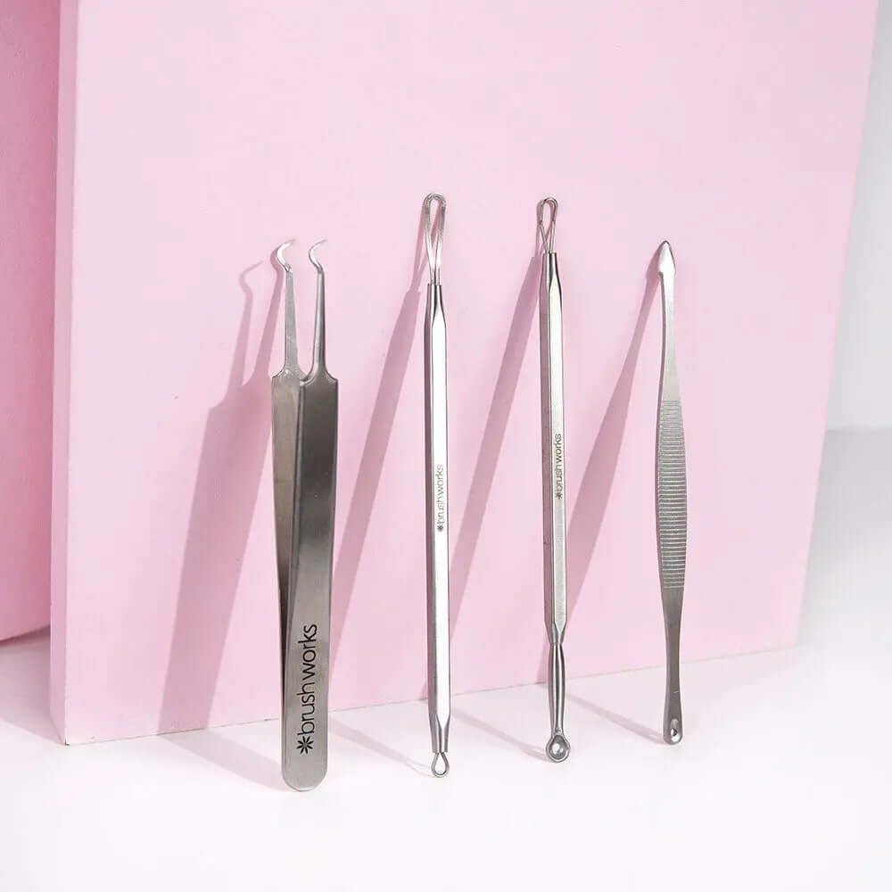 Brushworks Blackhead and Blemish Remover Set featuring four stainless steel skin tools on a pink background.