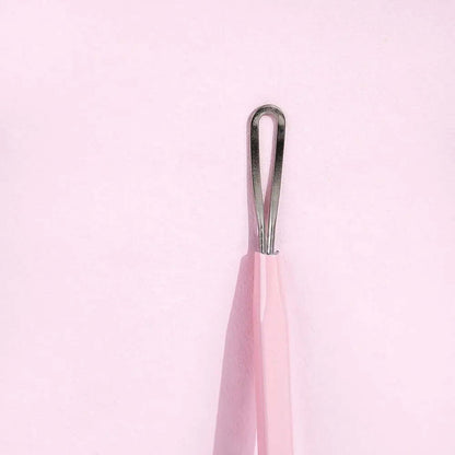 Brushworks Black Head Removal Tool with ergonomic design for effective blackhead removal, shown against a pink background.