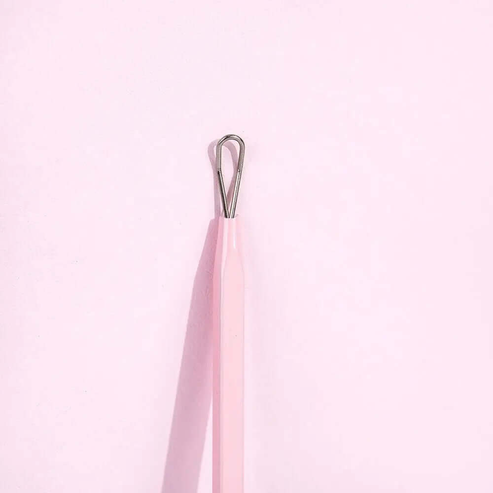 Brushworks Black Head Removal Tool with ergonomic design for safe and effective blackhead removal, against a pink background.