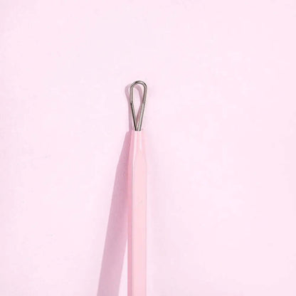 Brushworks Black Head Removal Tool with ergonomic design for safe and effective blackhead removal, against a pink background.
