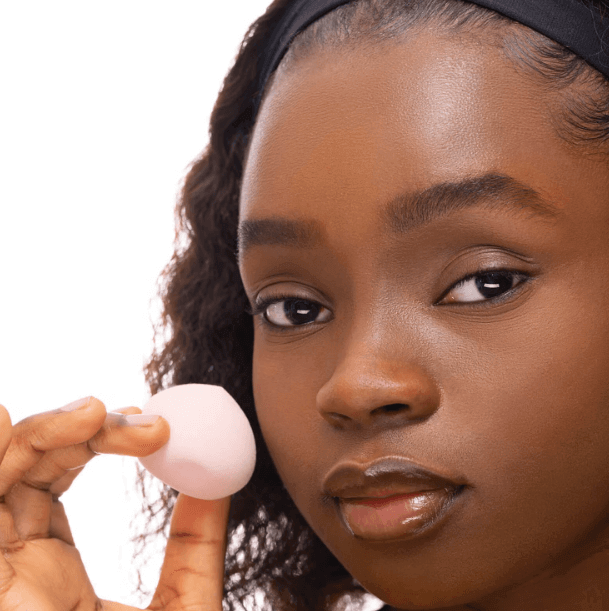 Model holding Brushworks Blending Drop sponge, showcasing its innovative design for perfect makeup blending.